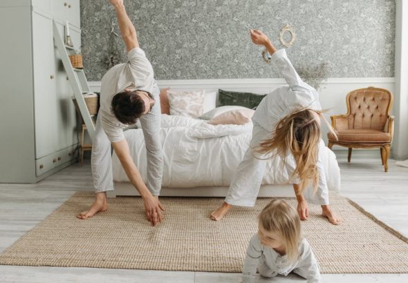 A family stretches together in a cozy bedroom, enjoying morning activities.